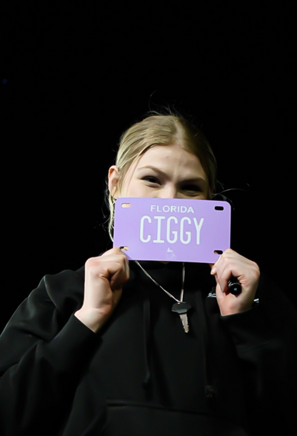 Custom motorcycle vanity plate, lavender and white with text "ciggy"