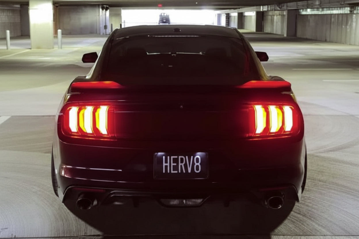 Back view of a black car with red taillights in an underground parking garage.